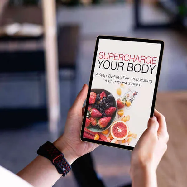 A hand holding a tablet that shows the e-book cover Supercharge Your Body